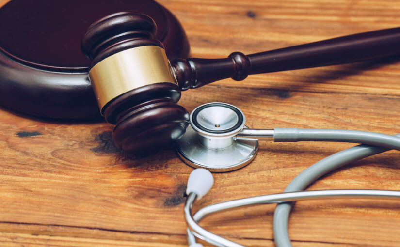 Stethoscope and judge's gavel on wooden desk symbolizing a medical malpractice lawsuit or doctor negligence claim.