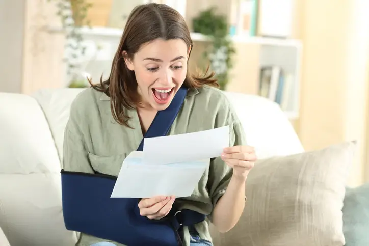 Injured woman smiling as she reads car accident settlement letter