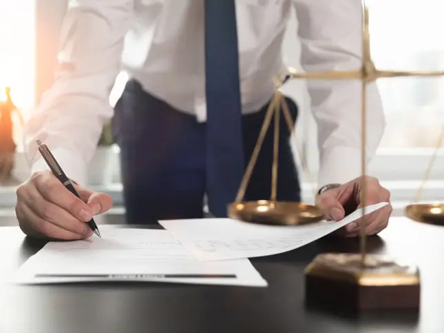 Houston slip and fall lawyer reviewing documents and signing paperwork beside scales of justice