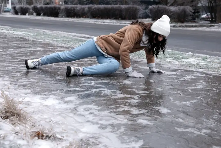 Woman on the ground after slipping on icy sidewalk in a slip and fall accident