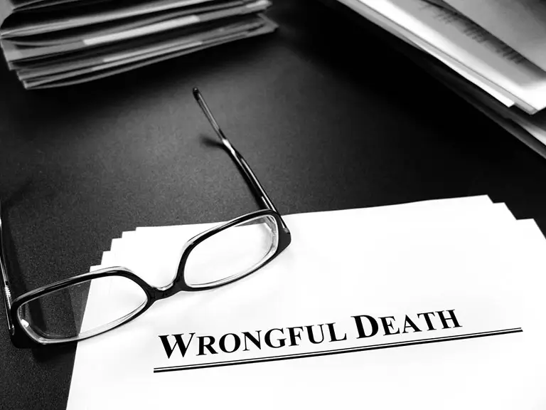 Glasses resting on wrongful death legal document on attorney desk